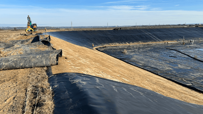 Black liner material being removed from a former pond with machinary