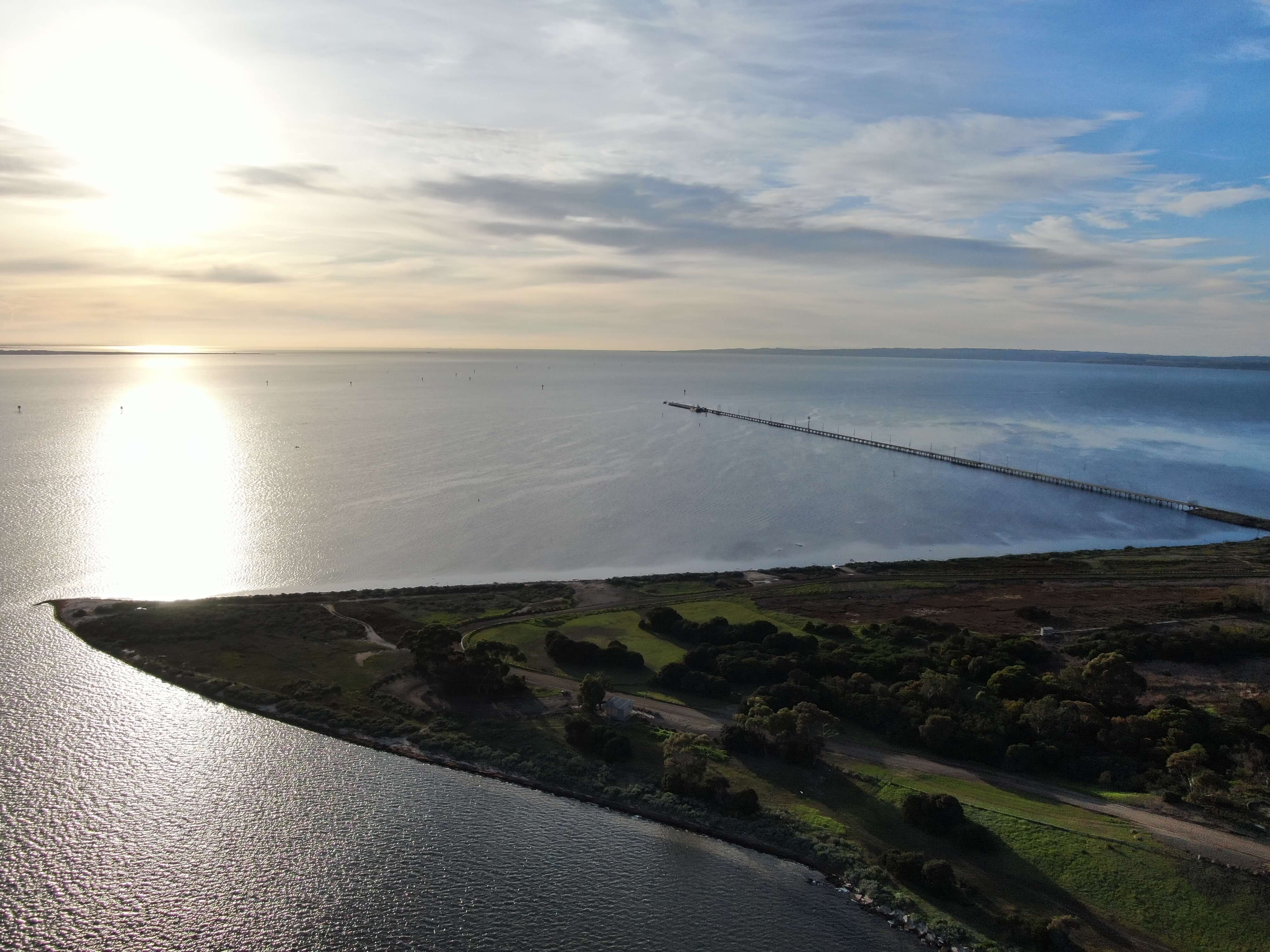 Image of a sunrise across Corio Bay, featuring a jetty and point of land